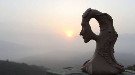 Experience the captivating interplay of light and shadow in this sculptural clay artwork.  The piece depicts fog-covered hill