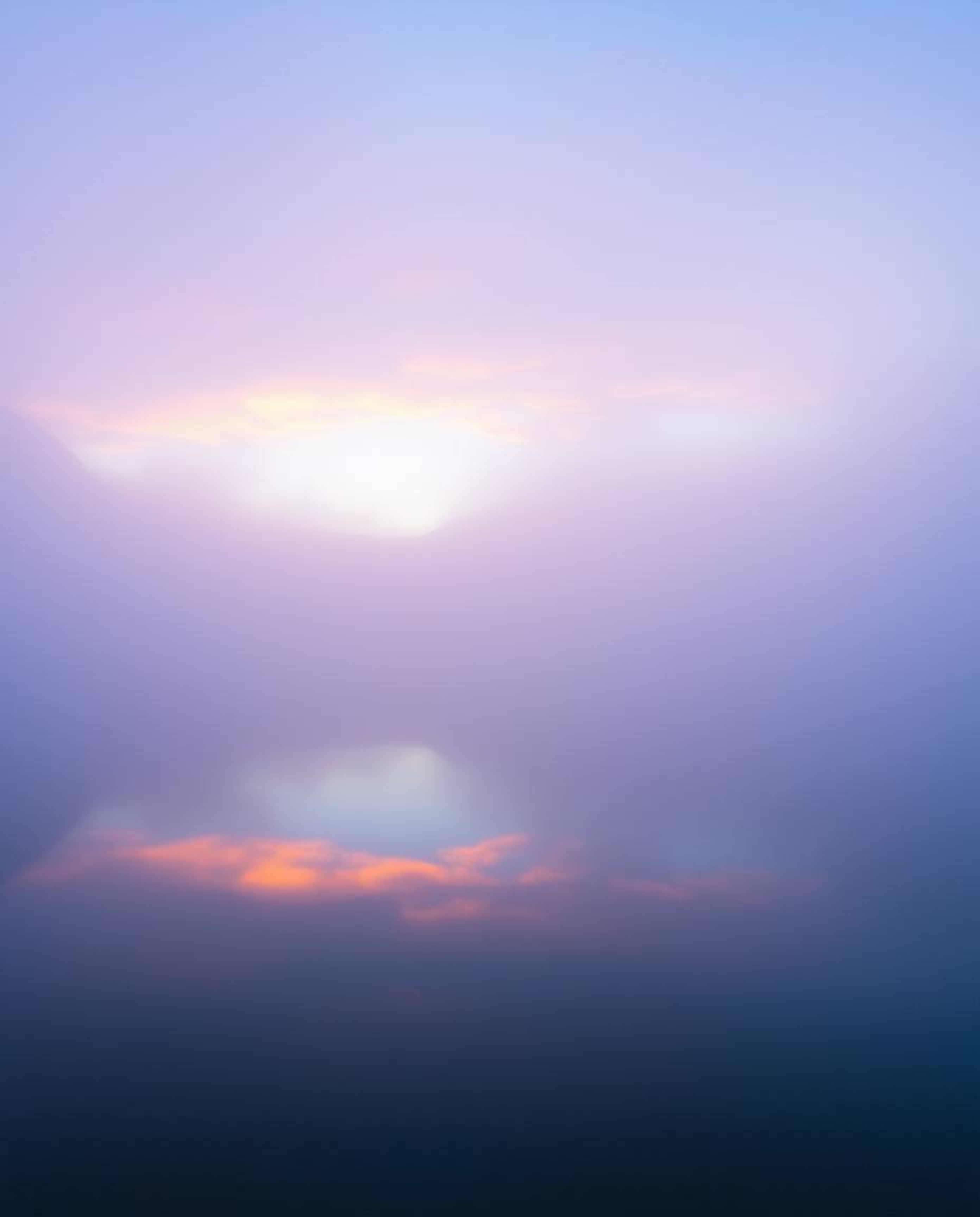A mysterious landscape shrouded in thick fog, dominated by a cool color palette of blues, greens, and purples. The low visibi