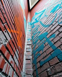A captivating low-angle perspective captures a brick wall adorned with warm terracotta hues contrasted against vibrant teal g