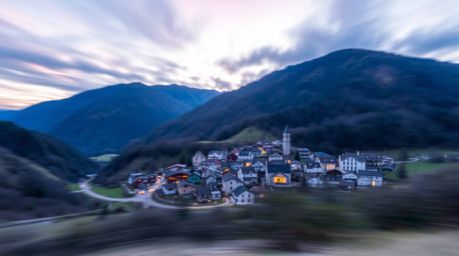 Discover a captivating long exposure photograph of a charming village nestled in a valley, bathed in the vibrant hues of a co