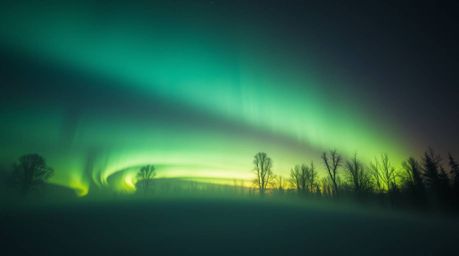 Witness the breathtaking spectacle of the Northern Lights emerging during a vibrant sunset. Volumetric lighting dramatically 