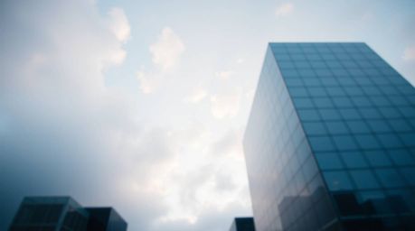 A modern glass building seamlessly dissolves into the soft, cloud-filled sky, creating a mesmerizing visual. This architectur