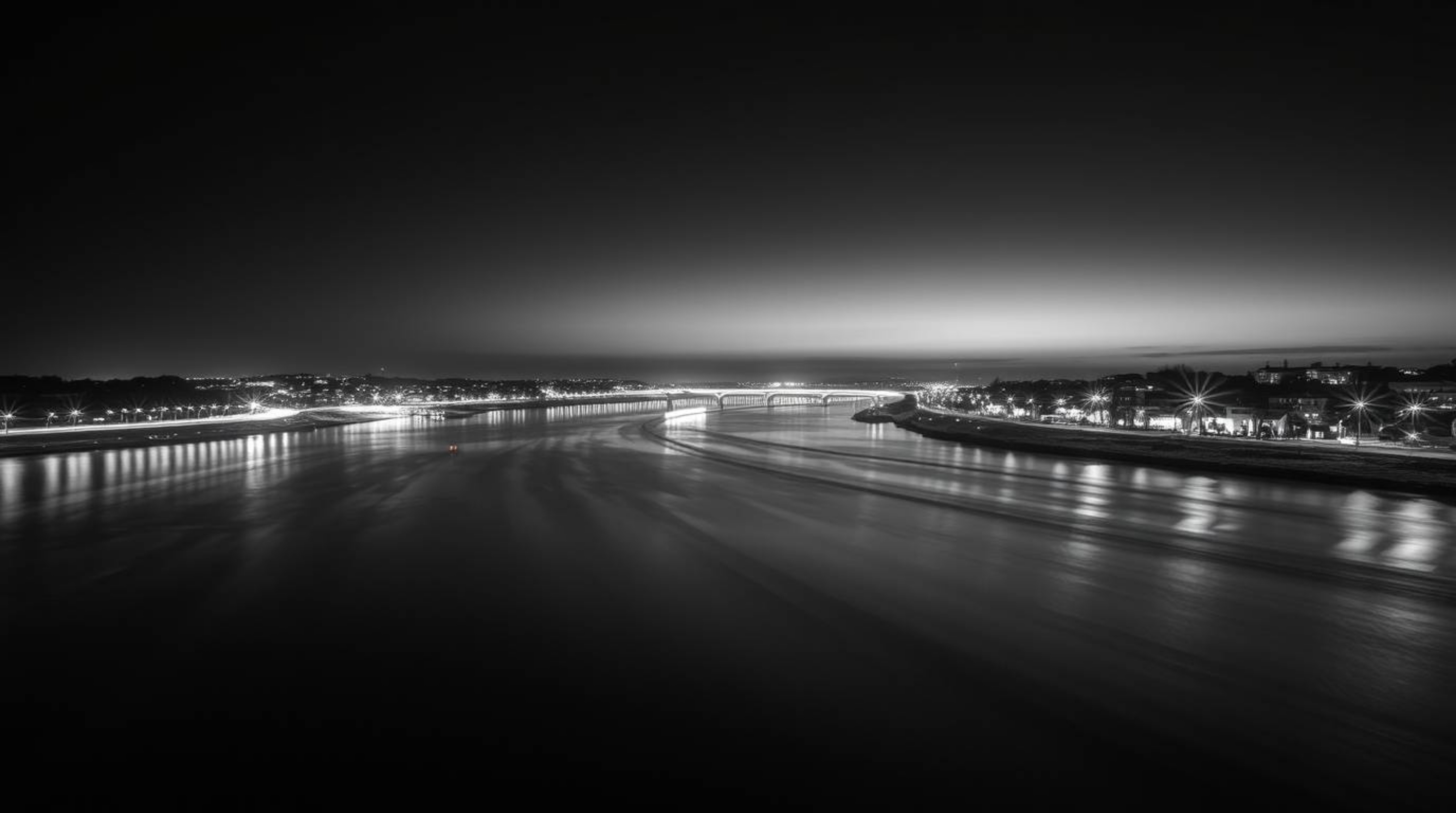 A captivating black and white long exposure photograph showcases a river delta bathed in the ethereal glow of twilight.  The 
