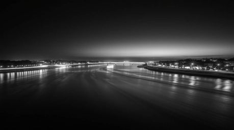 A captivating black and white long exposure photograph showcases a river delta bathed in the ethereal glow of twilight.  The 