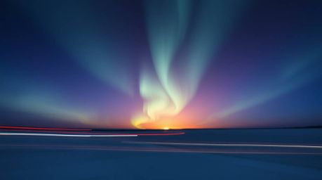 A stunning long exposure photograph showcasing the ethereal beauty of the Northern Lights dancing above a vibrant sunset sky.