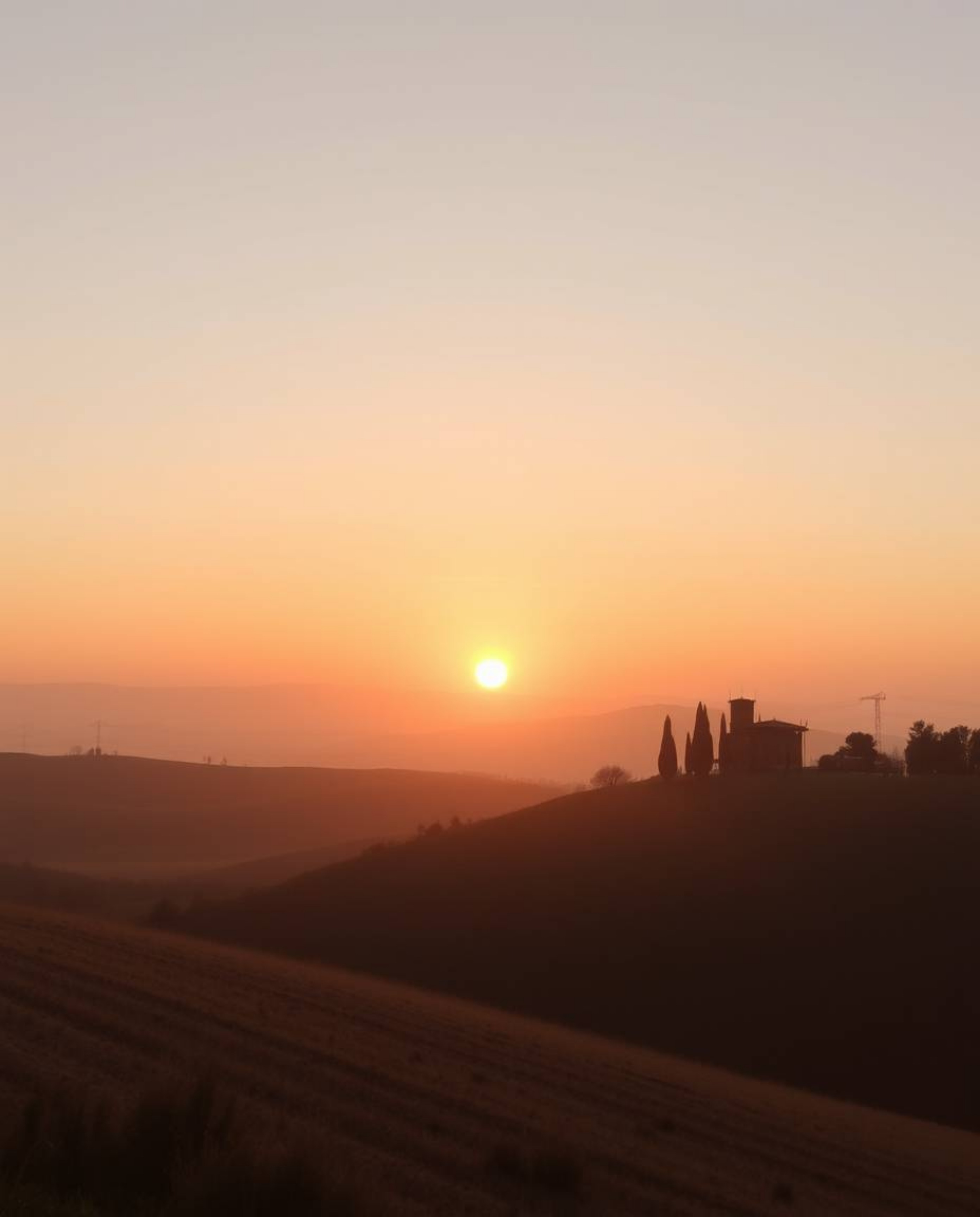 This is an extreme macro close-up of a delicate watercolor painting depicting a sunset over misty, rolling hills in Tuscany. 