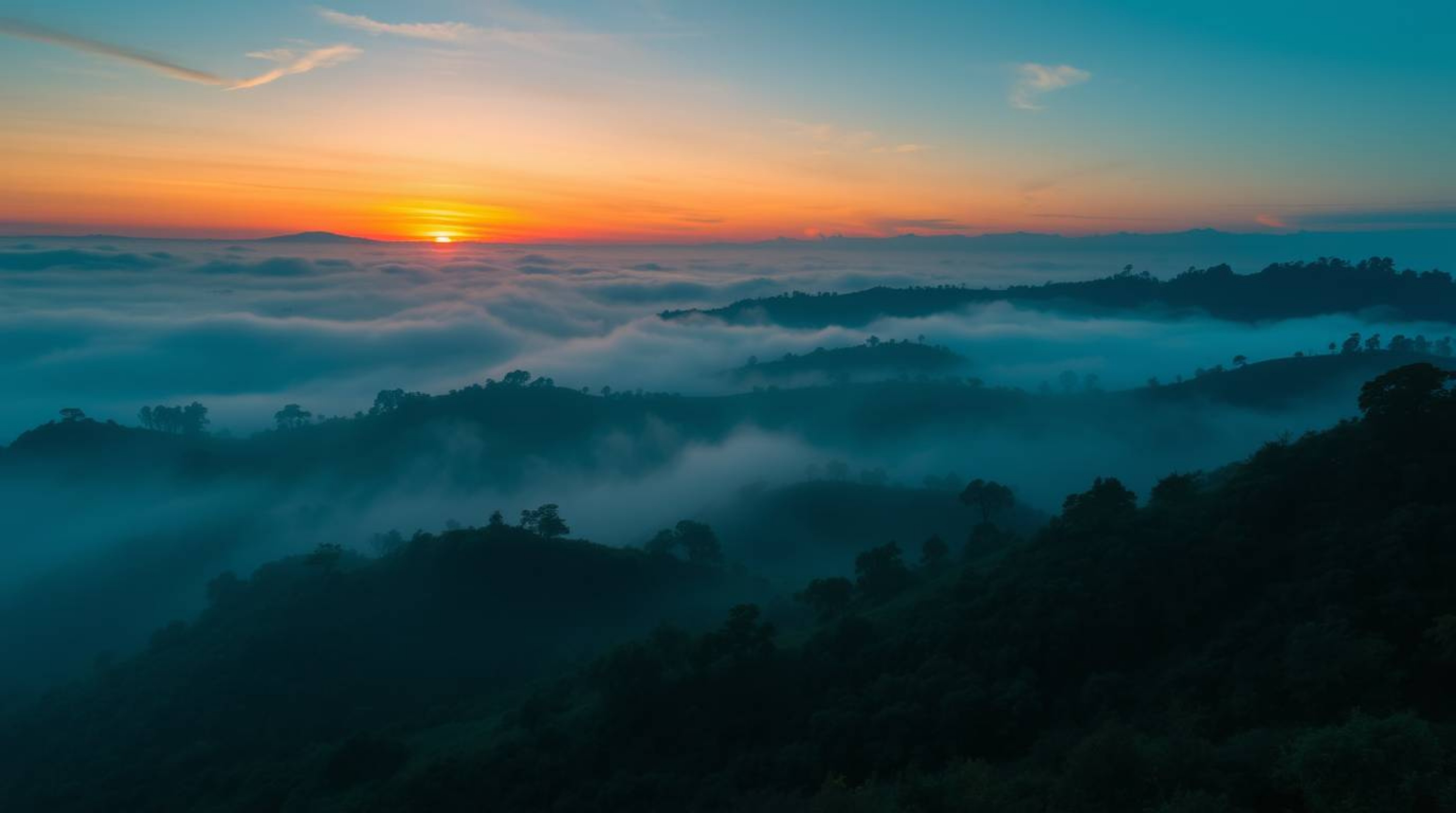 Capture the essence of professional photography with rich, deep teal tones and fog-covered hills illuminated by a breathtakin