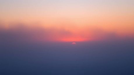 Witness the ethereal beauty of the Northern Lights subtly emerging from a thick fog over a breathtaking sunset sky.  This cap