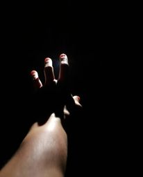 A captivating image depicts a hand reaching out from darkness towards a source of intense light. The strong, direct light cas