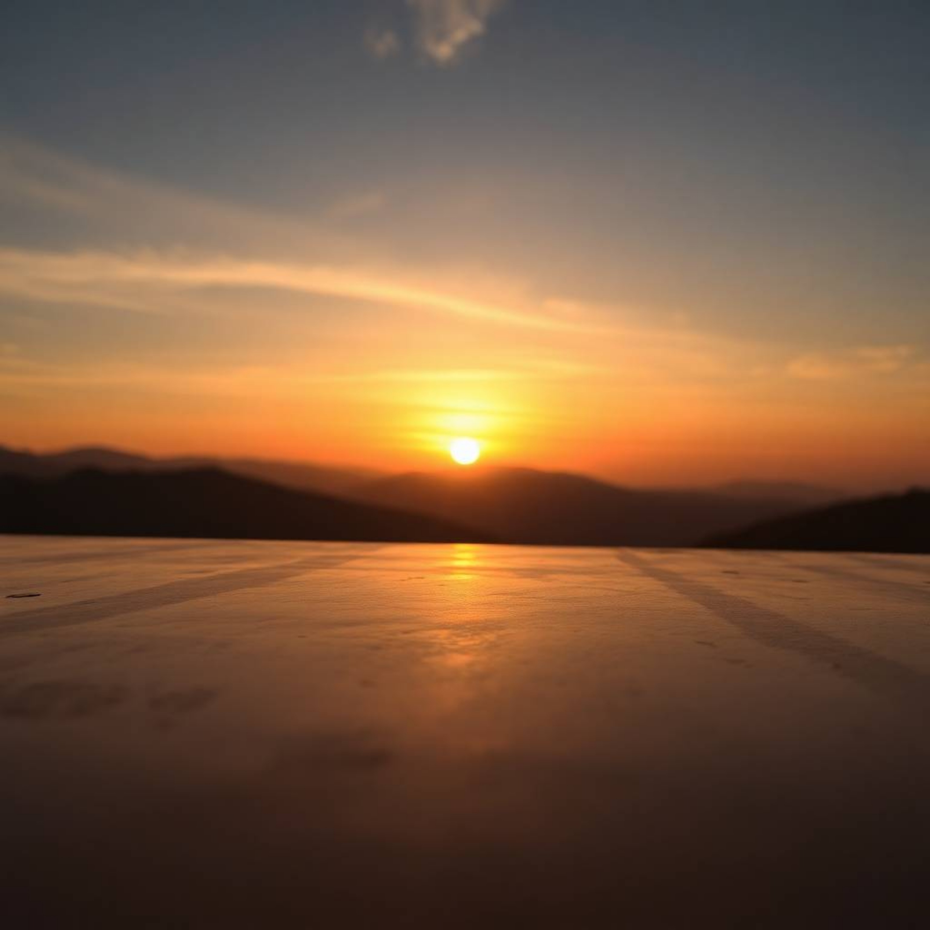 A stunning close-up captures a serene sunset over a tranquil mountain valley, rendered with a smooth gradient transition on a