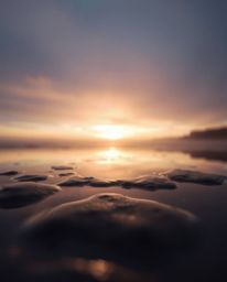 A soft cinematic sunset sky is beautifully mirrored in the tidal pools on a beach. This photograph uses a soft focus and a ha