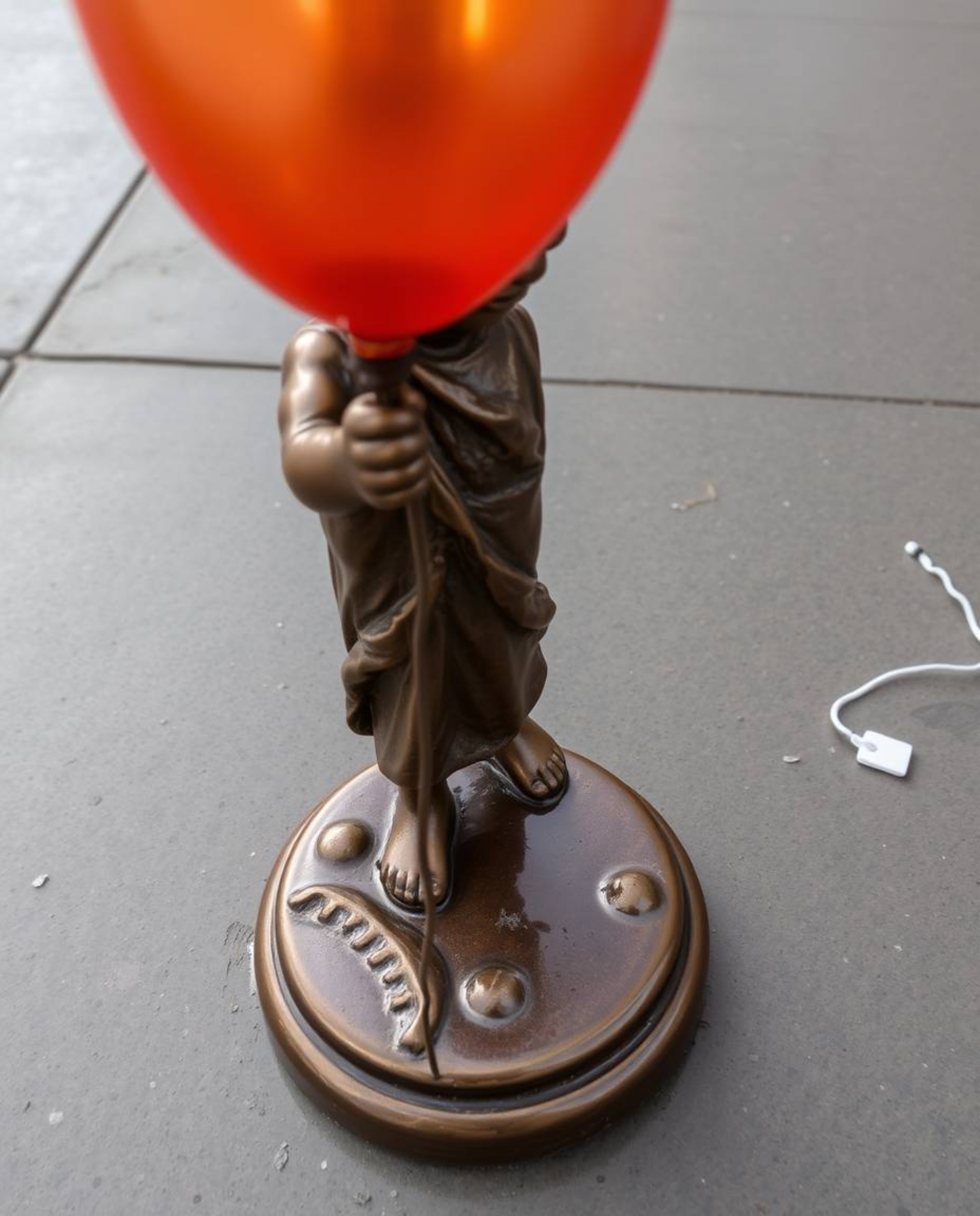 A captivating image of a child holding a vibrant balloon against a textured cast bronze surface.  The low-angle perspective a
