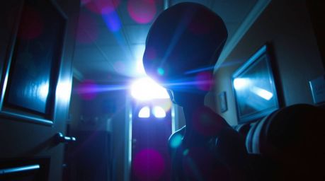 Discover a chilling image of an alien inhabiting a seemingly ordinary suburban house.  This unsettling scene features vibrant