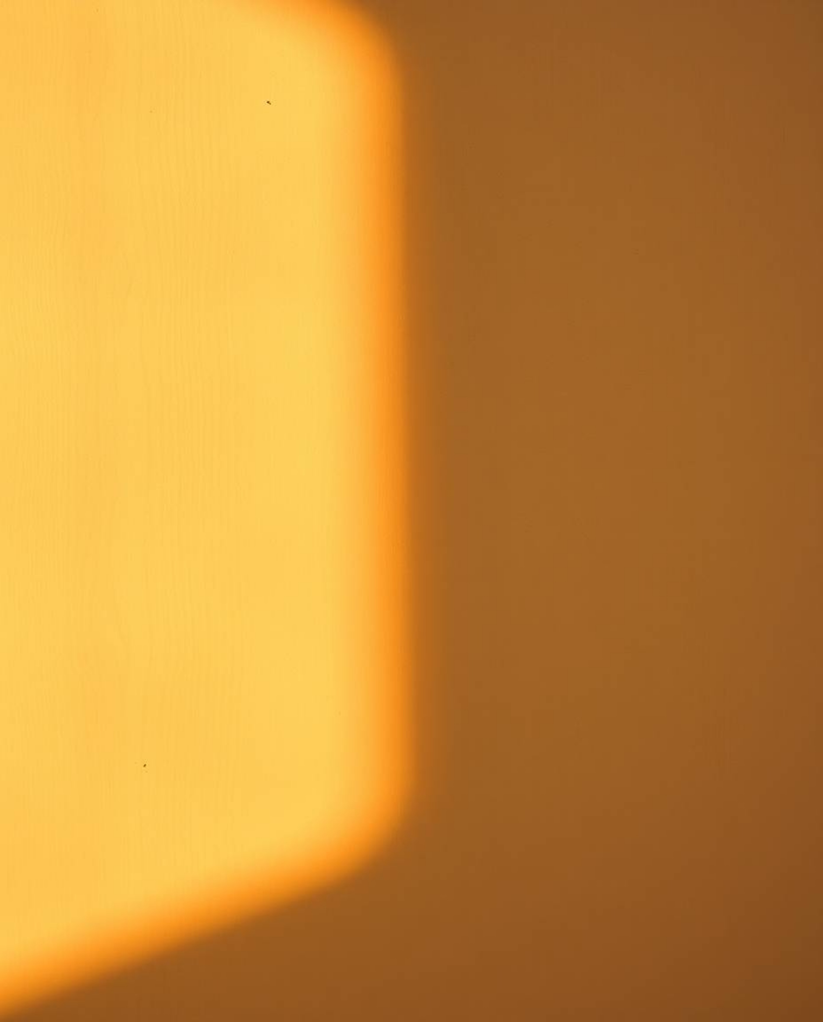 Warm golden hour light illuminates a cast bronze surface showcasing a geometric pastel gradient wallpaper, reminiscent of a s