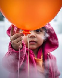 A captivating extreme macro photograph showcases a child holding a balloon, enveloped in thick fog.  The image is bursting wi