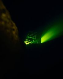 A breathtaking extreme macro close-up captures the haunting beauty of a shipwreck illuminated deep underwater. The scene show