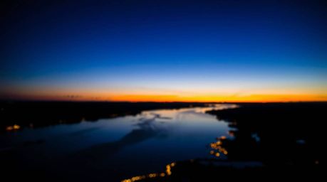 A captivating close-up silhouette of a river delta bathed in the warm glow of twilight.  The backlighting accentuates the int