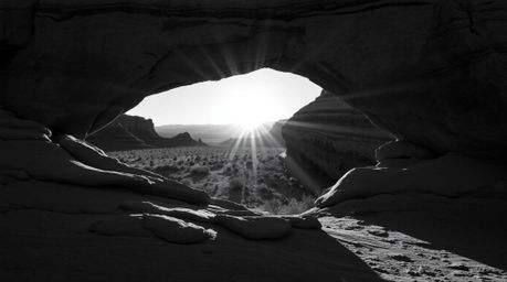 Classic black and white photography evokes a sense of timeless elegance by capturing a breathtaking desert sunset framed by a