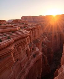 A sunset bathes sandstone canyon cliffs in a radiant and luxurious light, characterized by a strong, hard quality and a warm 