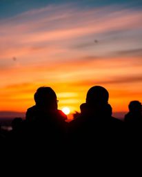 From a stunning overhead perspective, silhouetted figures stand out against a vibrant sunset backdrop as delicate snowflakes 