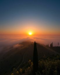 This photograph provides a stunning high-angle perspective, looking down upon a serene sunset over the misty, rolling hills o