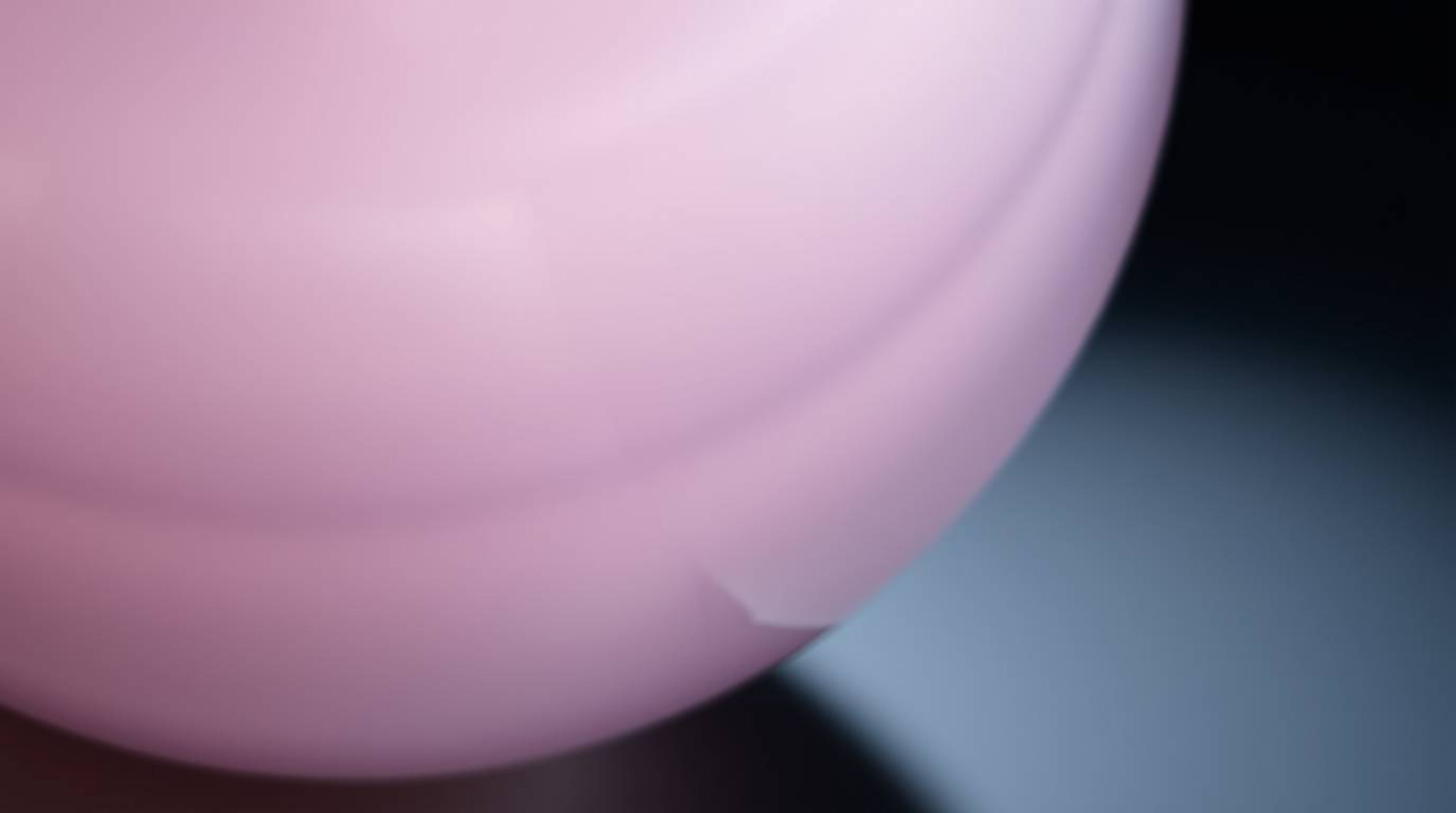 This close-up detail showcases a glass object beautifully reflecting smooth gradient textures in soft pastel colors. The gent