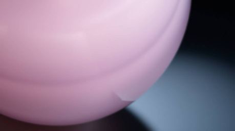 This close-up detail showcases a glass object beautifully reflecting smooth gradient textures in soft pastel colors. The gent