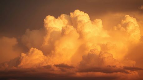 A captivating close-up reveals the natural earth tones of thunderstorm clouds dramatically lit by the setting sun.  Browns an