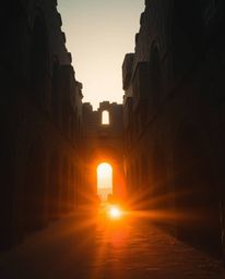 An eerie, creepy atmosphere is created by the warm golden hour light as a sunset casts shadows through ancient stone ruins. T