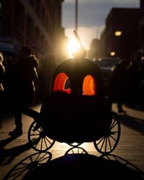 Capture the magic! This candid street photography shot features a silhouette of a pumpkin transforming into a carriage, backl