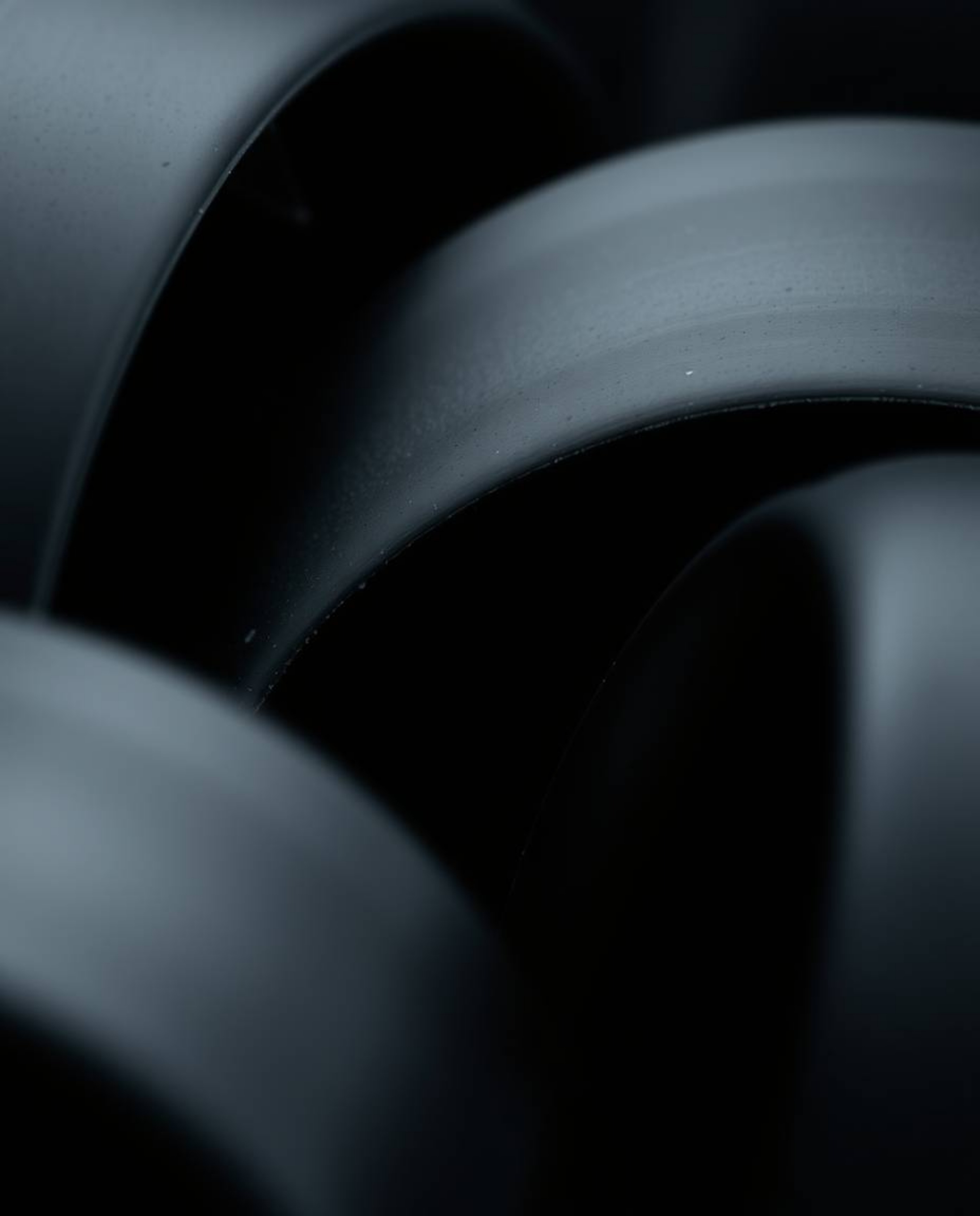 Intensely jet-black abstract shapes captured in extreme macro close-up. High-contrast, low-key lighting creates dramatic shad