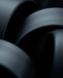 Intensely jet-black abstract shapes captured in extreme macro close-up. High-contrast, low-key lighting creates dramatic shad