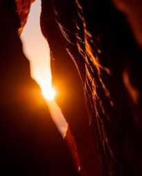 An extreme macro close-up shot showcases a sunset illuminating sandstone cliffs. The image employs dramatic backlighting, pos