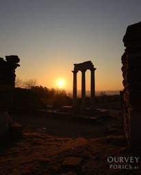 A warm autumn sunset casts long shadows across ancient stone ruins. The scene is earthy and cozy, rendered in soft light with