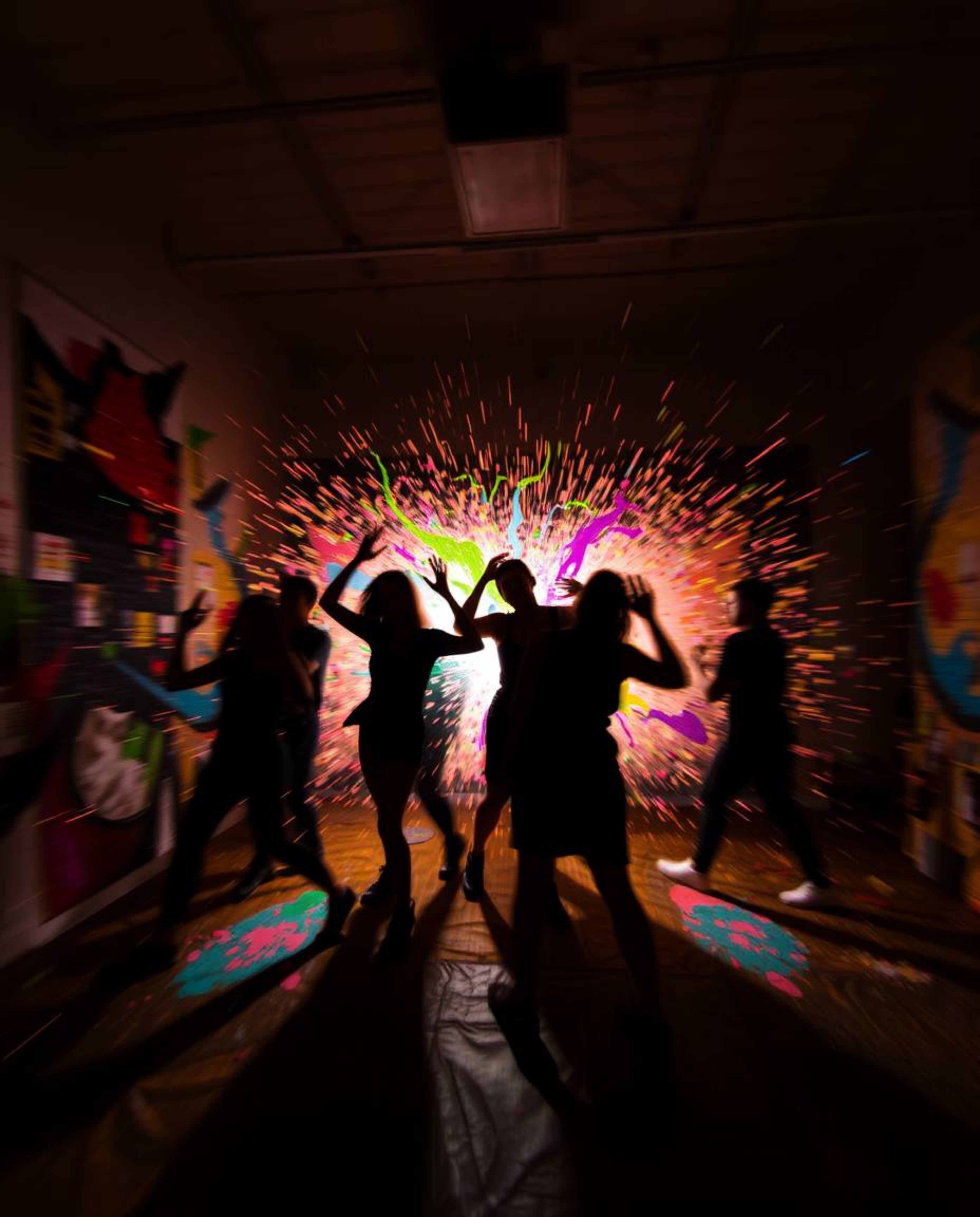 Witness a chaotic explosion of color and movement in this dynamic composition. Silhouetted figures are caught in the crossfir