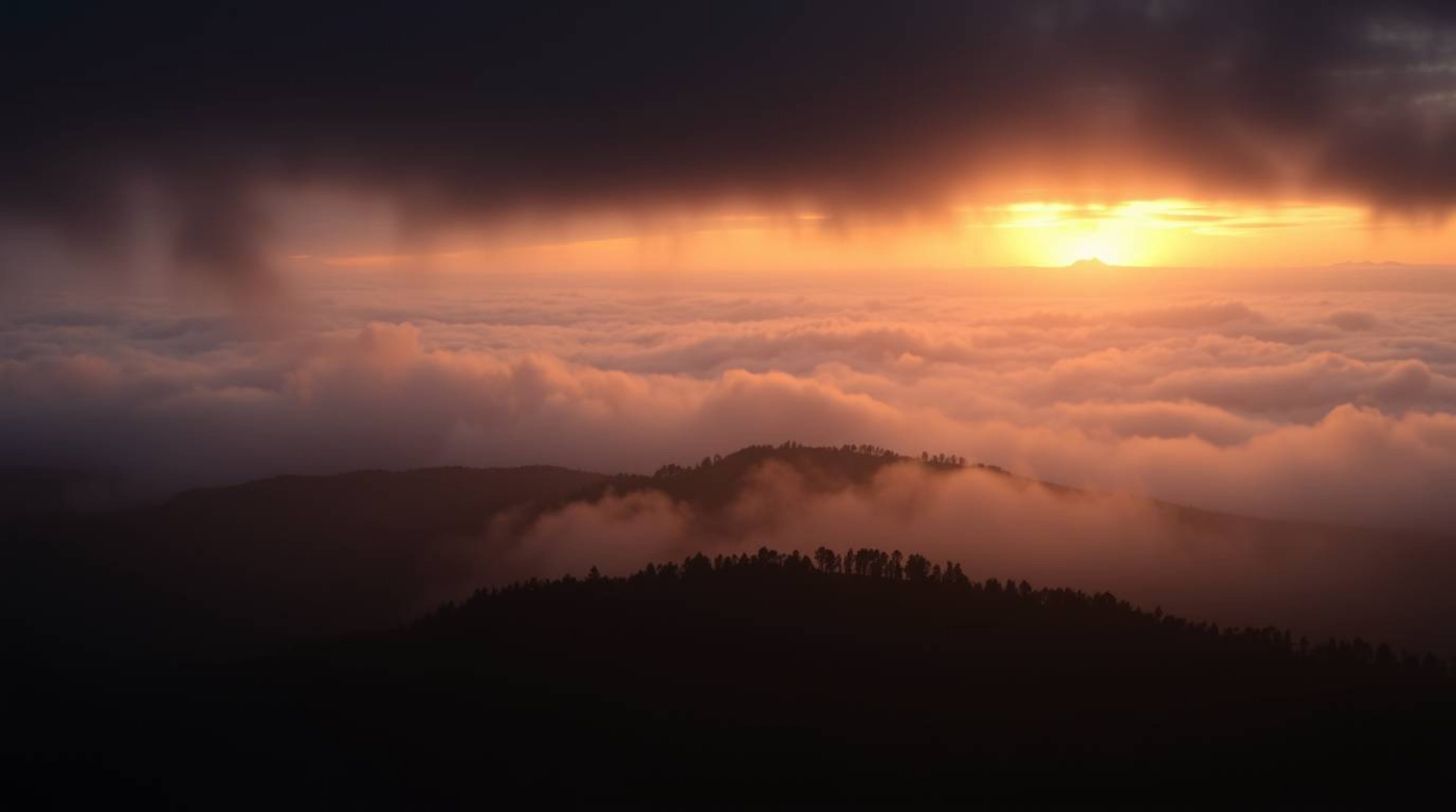 Witness the breathtaking beauty of fog-covered hills emerging from a stormy sunset.  Intense, dramatic weather creates a scen