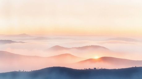 A delicate watercolor painting capturing the ethereal beauty of fog-covered hills at sunset. The artwork utilizes strong, har
