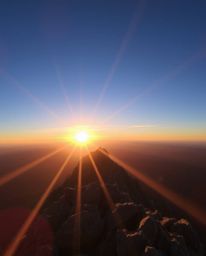 Witness a graceful and elegant sunset as seen from a high alpine peak. This captivating scene is enhanced by a bright lens fl