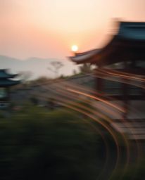 Witness an ethereal long-exposure photograph of a serene Zen garden at sunset. This captivating image features artistic motio