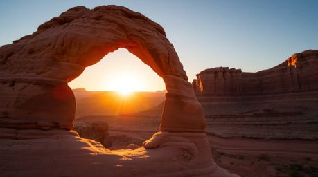 Experience the breathtaking beauty of a sunset viewed through a natural desert rock arch.  This captivating image showcases t