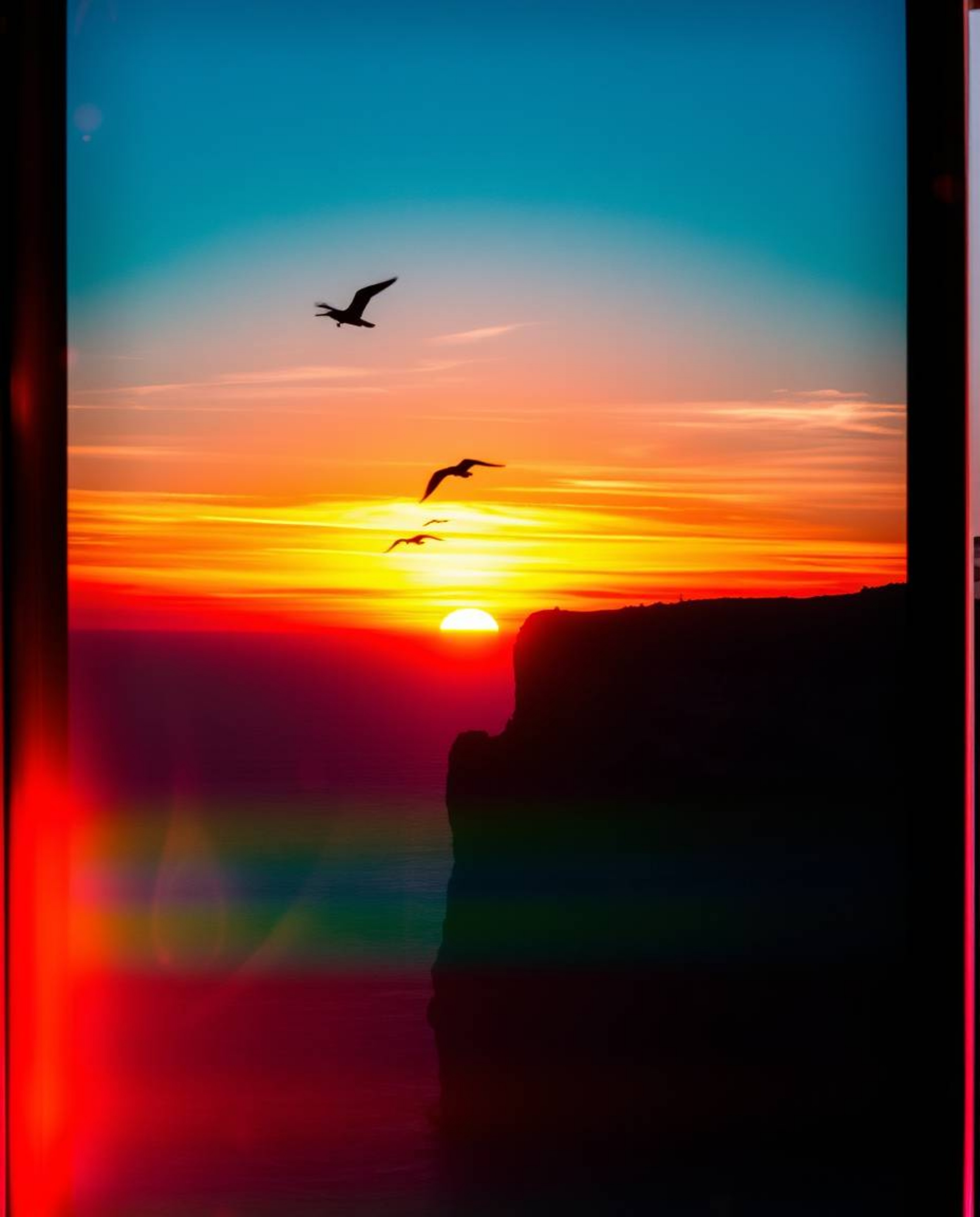 This is a dramatic cinematic sunset over a coastal cliff, where soaring birds are beautifully silhouetted against vibrant lig