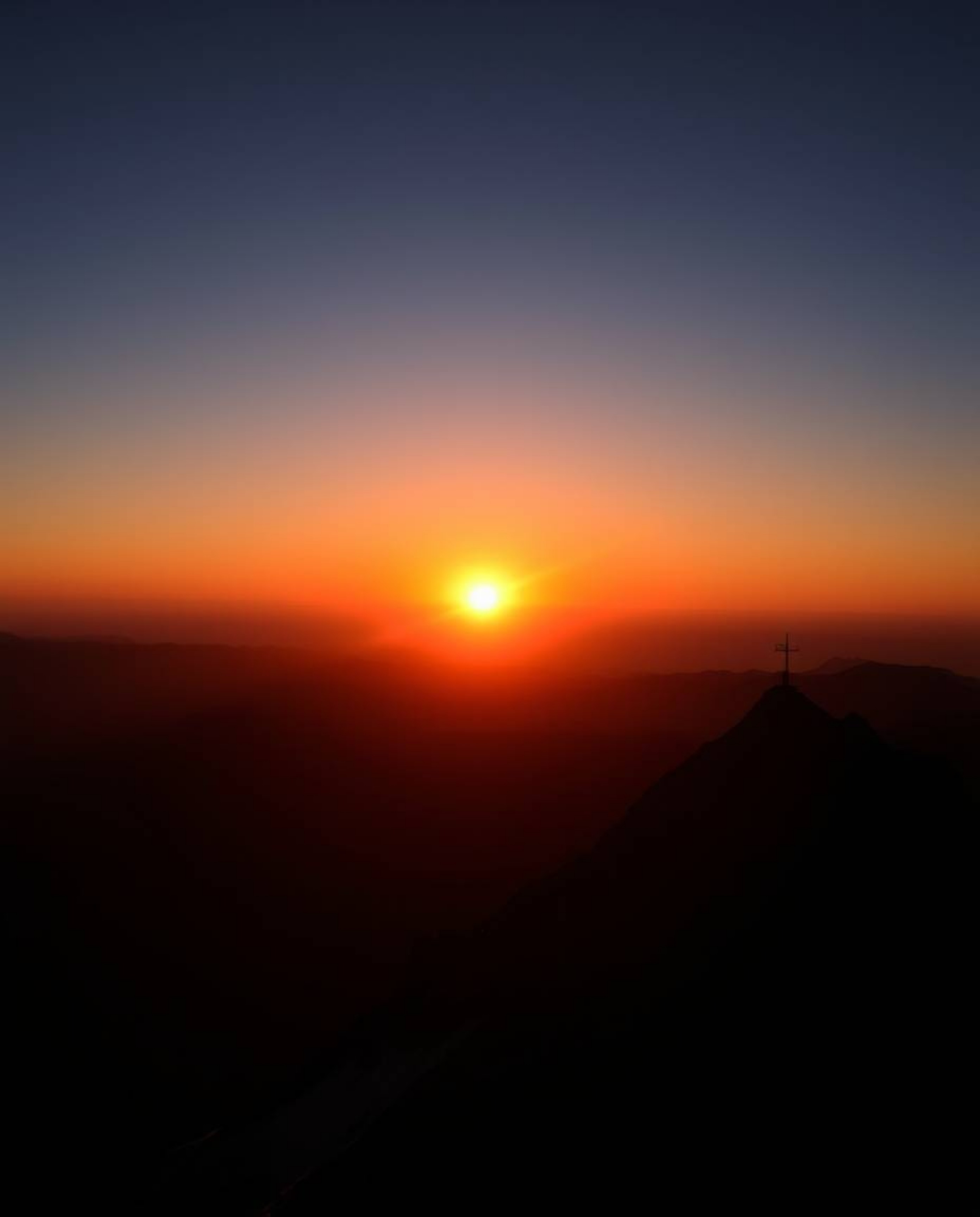 Witness a high-contrast, low-key lit sunset from the stunning vantage point of a high alpine peak. This composition is both g