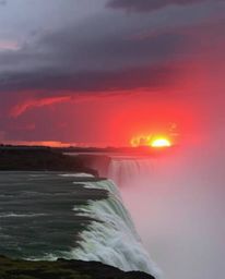 Experience a scene of intense weather as warm sunlight contrasts with stormy skies while the sun sets behind a dramatic water