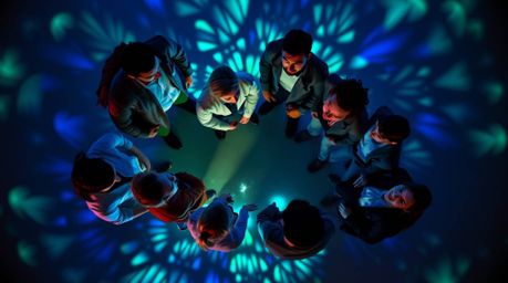 An overhead shot reveals a circle of diverse misfit heroes, illuminated by abstract patterns in cool blues, greens, and purpl