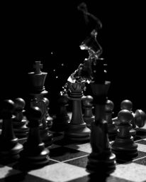 This captivating image features a chessboard and chess pieces frozen in a moment of mid-destruction, rendered in classic blac