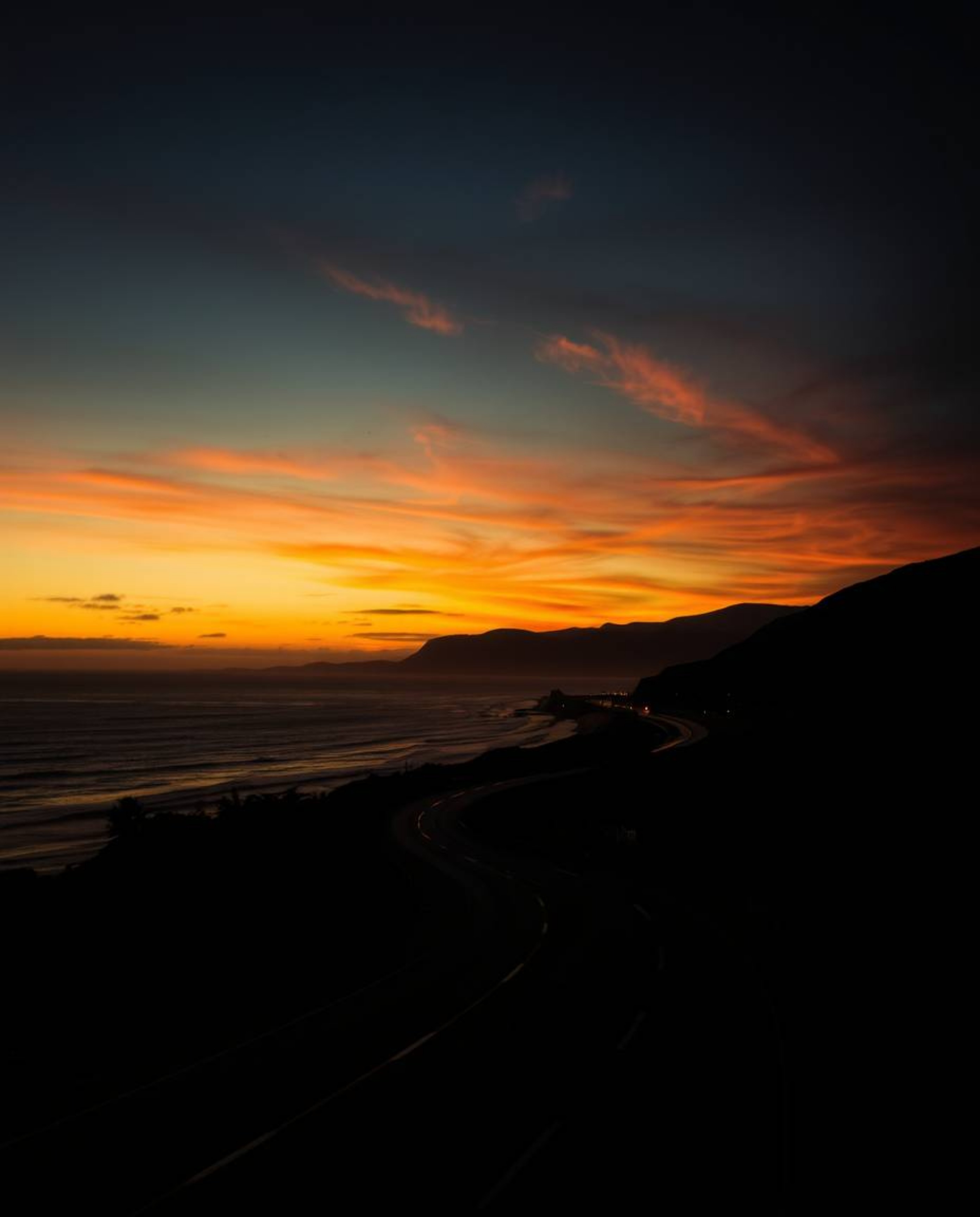 This artwork is a strong, moody style depiction of creative light art, featuring a sunset sky over a winding coastal highway.
