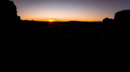 A stunning high-resolution stock photo depicting a rocky canyon at sunset. The image showcases intense jet black tones and de