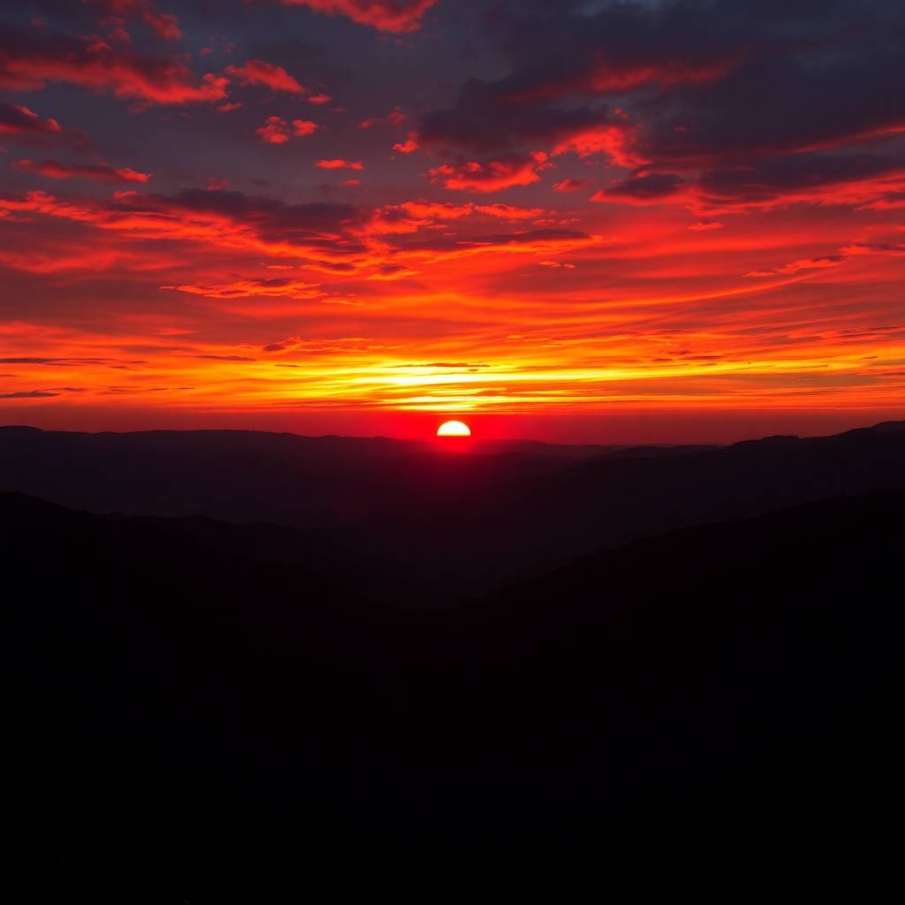 Experience the breathtaking beauty of a sunset over a tranquil mountain valley.  Witness electric, vivid colors painted acros