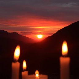 Capture the serene beauty of a sunset over a quiet mountain valley, enhanced by the warm, inviting glow of candlelight and th
