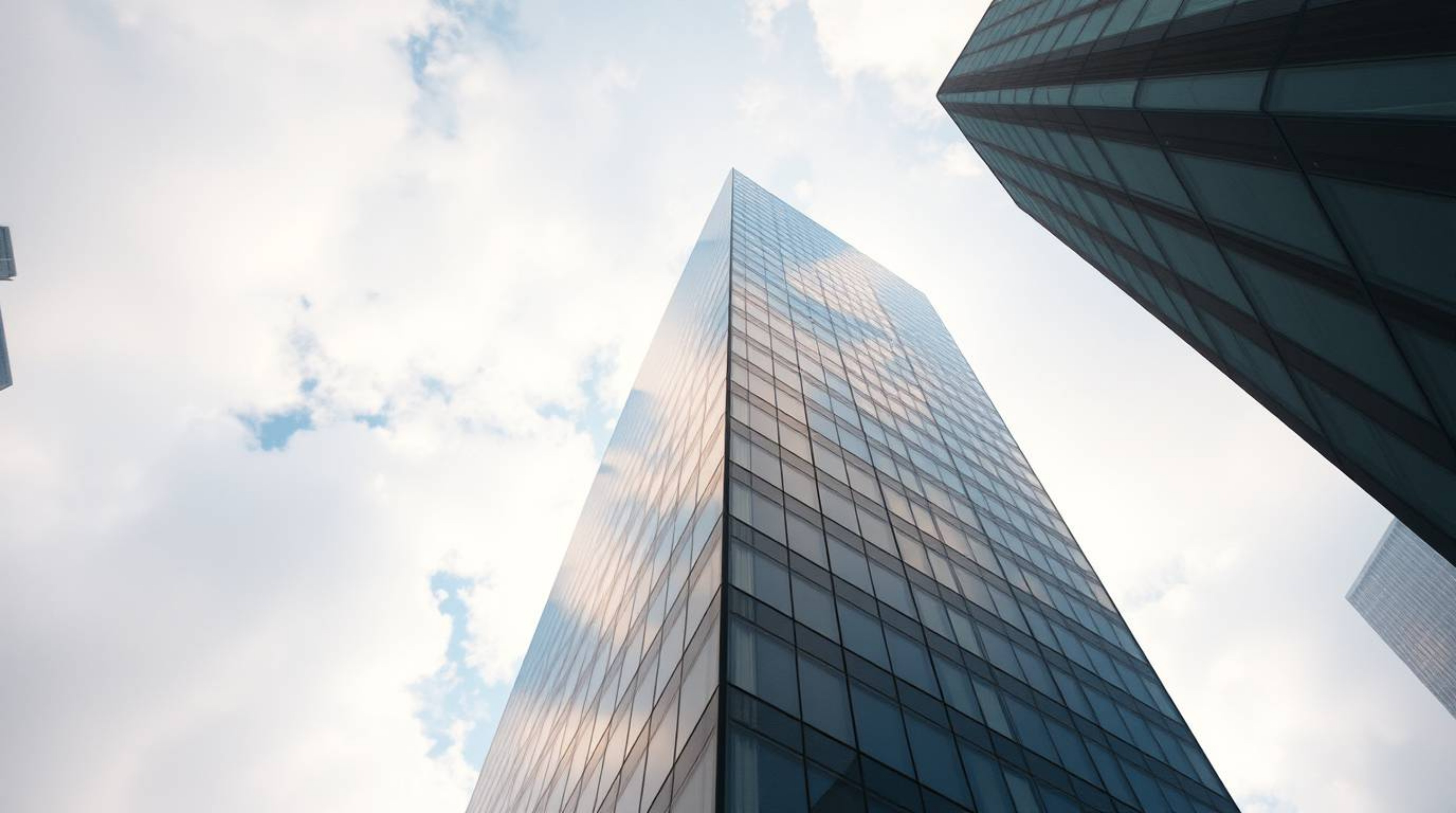 A modern glass building gracefully merges with the sky, its structure seamlessly blending with soft clouds, evoking a sense o